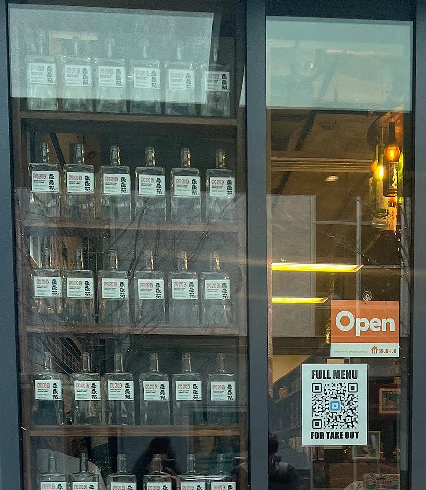 Shelves of labelled Gyo Gyo En bottles lined up in the shop window on 8th Avenue